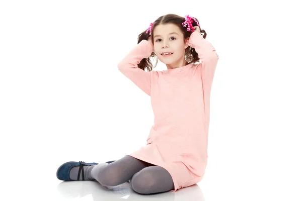 Kis lány ül a földön és kiegyenesíti a haj. — Stock Fotó