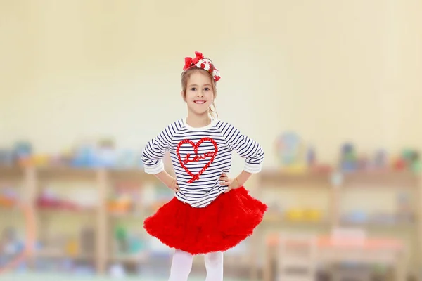 Little girl in a red skirt and bow on her head. — Stock Photo, Image