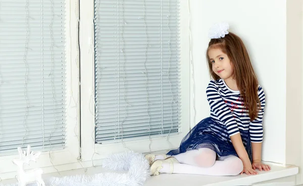 Triste petite fille assise près de la fenêtre . — Photo