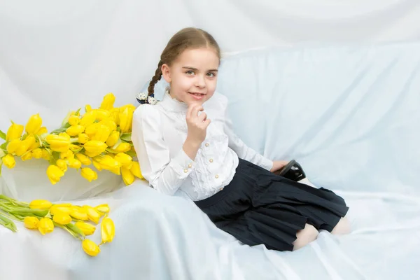 Een student van de ijverige schoolmeisje met gele tulpen zit op t — Stockfoto