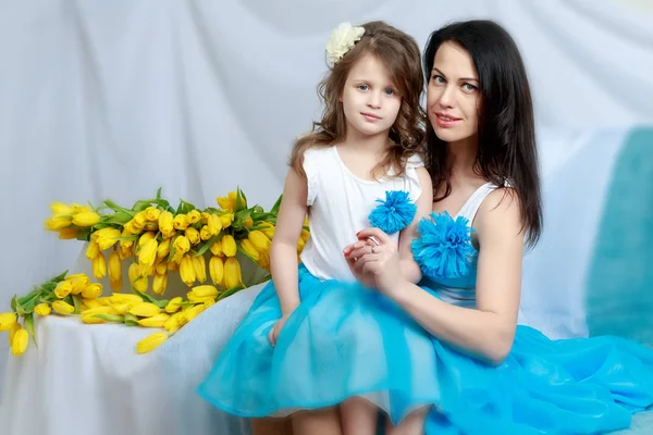 Anne ve kızı bir buket çiçek ile kanepede.