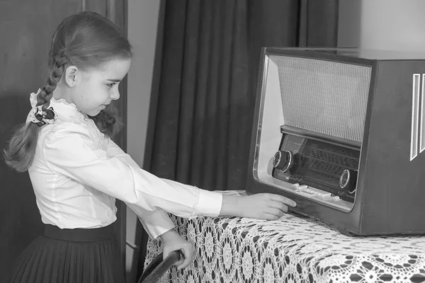 Little girl listens to old radio.