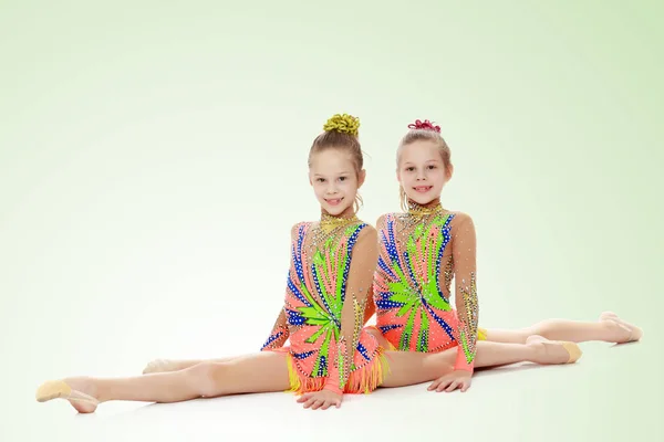 Dwie dziewczyny gimnastyczka siedzi na podziały. — Zdjęcie stockowe