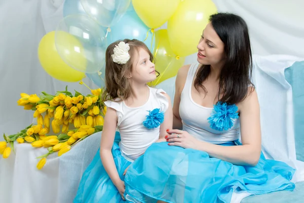 Mamá e hija en el sofá con un ramo de flores . —  Fotos de Stock