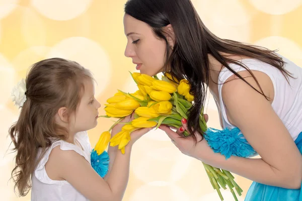 Mutter und Tochter riechen gelbe Tulpen. — Stockfoto