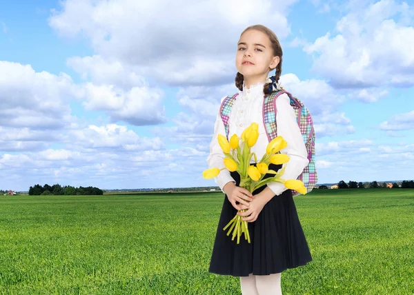 Школьница с букетом цветов и рюкзаком на ее шо — стоковое фото