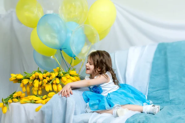 A menina no sofá com um buquê de flores . — Fotografia de Stock