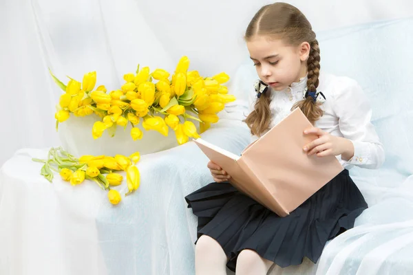 Een student van de ijverige schoolmeisje met gele tulpen zit op t — Stockfoto