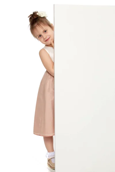 Ένα μικρό κορίτσι που κρυφοκοιτάζει από πίσω από το λάβαρο. — Φωτογραφία Αρχείου
