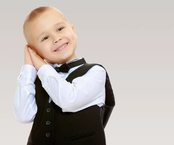 Trendy kleine jongen in een zwart pak met een stropdas. — Stockfoto