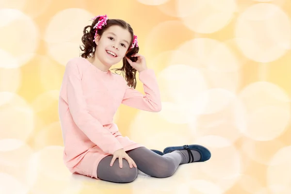 Little girl sitting on the floor and straightens hair. — Stock Photo, Image