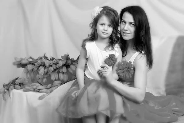 Maman et fille sur le canapé avec un bouquet de fleurs . — Photo