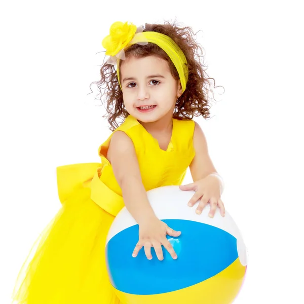 Gadis kecil bergaun kuning memegang bola — Stok Foto
