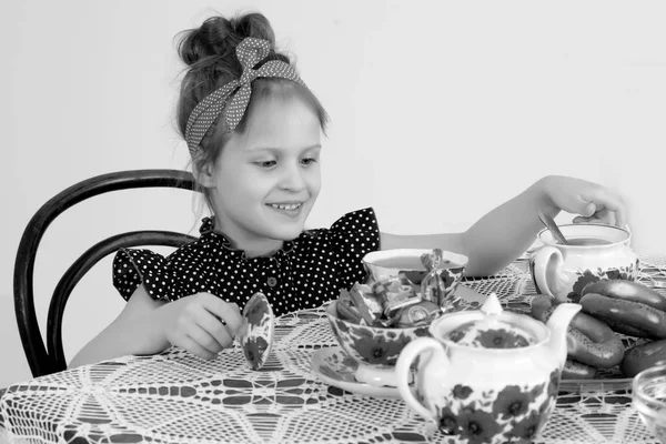 Meisje, drinken van thee op de tafel. — Stockfoto