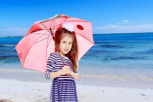 Liten flicka gömmer sig under ett paraply. — Stockfoto