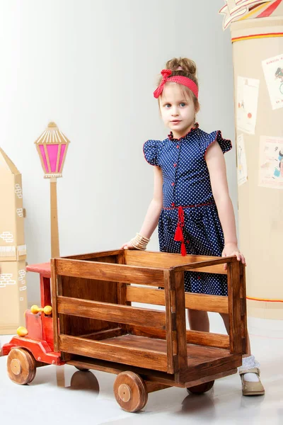 Little girl playing with a big wooden car. — Stock Photo, Image