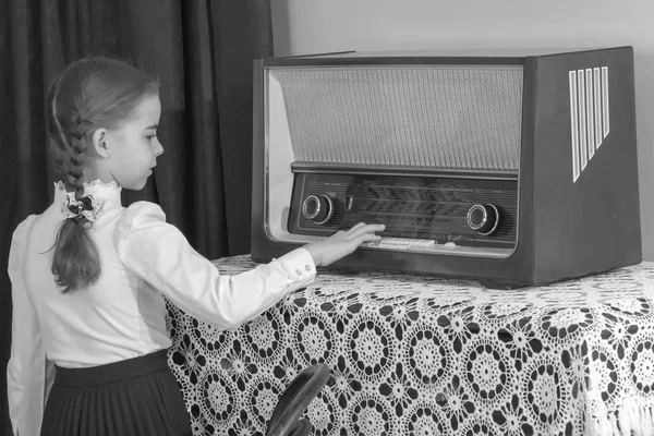 Little girl listens to old radio.