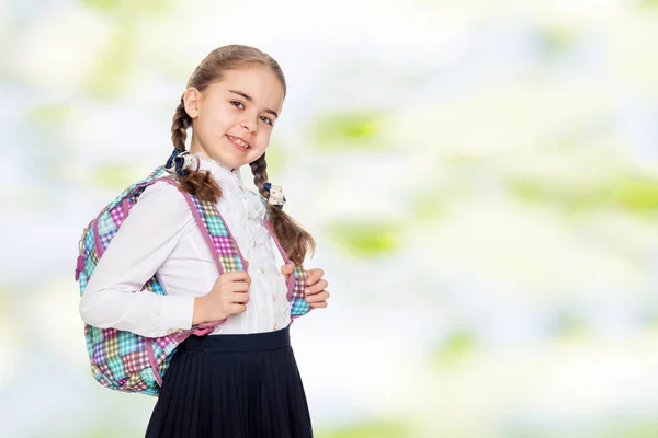 Bela colegial com uma mochila atrás dos ombros . — Fotografia de Stock