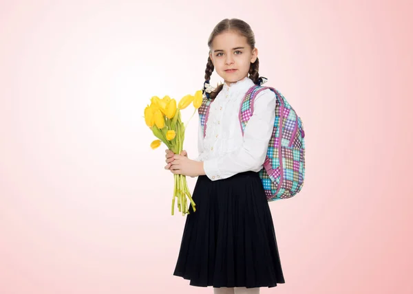 Школьница с букетом цветов и рюкзаком на ее шо — стоковое фото