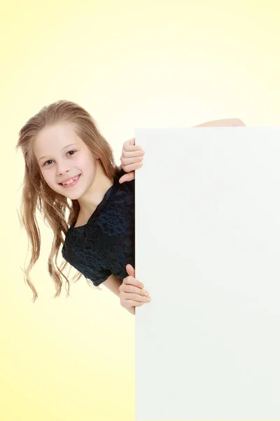 The girl peeks out from behind the banner. — Stock Photo, Image