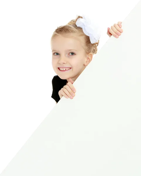 Девушка выглядывает из-за белого баннера . — стоковое фото