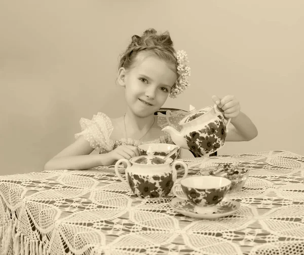 古いテーブルに紅茶を飲むかわいい女の子. — ストック写真