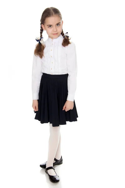 Een klein meisje in een witte jurk en een donkere rok. — Stockfoto