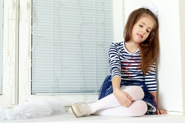 Sad little girl sitting by the window. — Stock Photo, Image