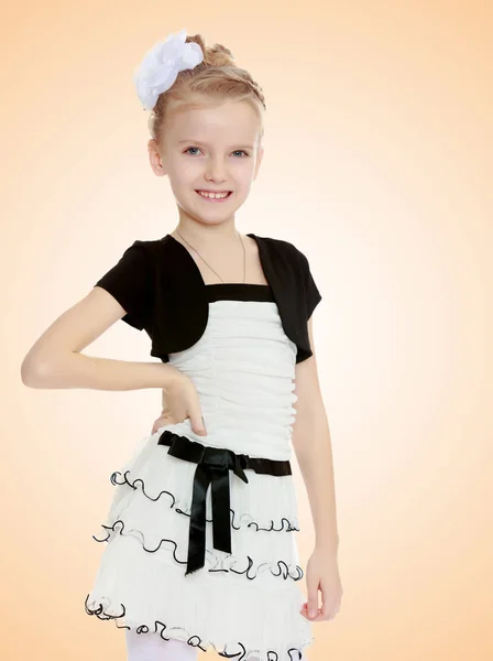 Beautiful little girl in a white short dress with a black belt. — Stock Photo, Image