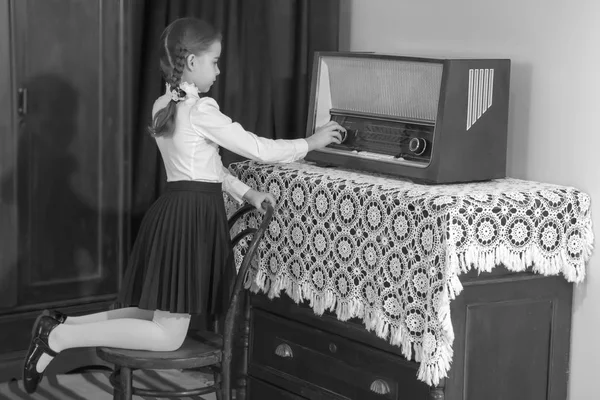 Little girl listens to old radio.