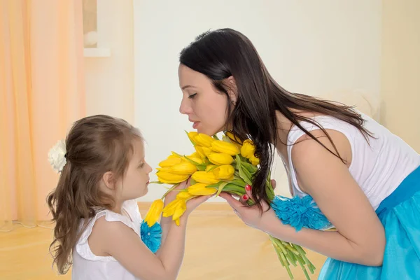 Mutter und Tochter riechen gelbe Tulpen. — Stockfoto