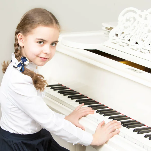 A girl from a music school plays the piano. — Stock Photo, Image