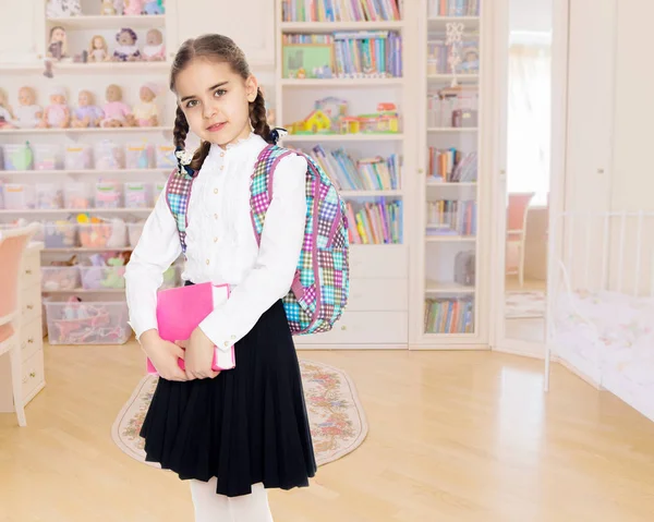 Het meisje is een schoolmeisje met een boek in haar handen. — Stockfoto
