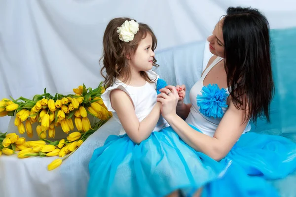 Mom and daughter on the sofa with a bouquet of flowers. — Stock Photo, Image