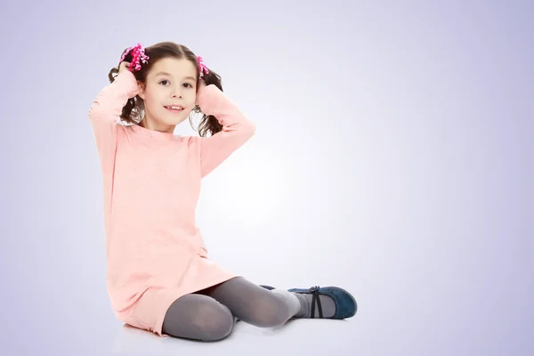 Niña sentada en el suelo y alisando el cabello . — Foto de Stock