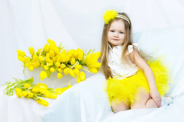 Uma menina com um buquê de tulipas amarelas . — Fotografia de Stock