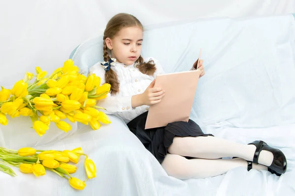 Pilný školačka student s žluté tulipány a sedí na t — Stock fotografie