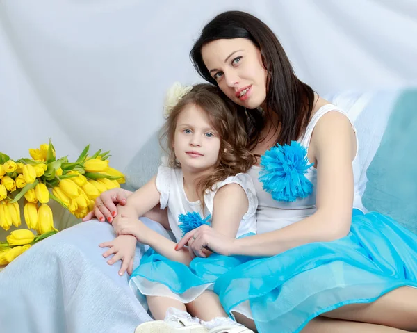 Anya és lánya a kanapéra egy csokor virágot. — Stock Fotó