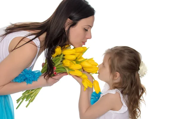 Mãe e filha cheirando tulipas amarelas . — Fotografia de Stock