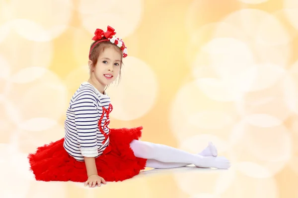 Little girl in a red skirt and bow on her head. — Stock Photo, Image