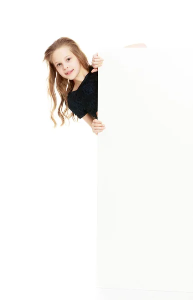 The girl peeks out from behind the banner. — Stock Photo, Image