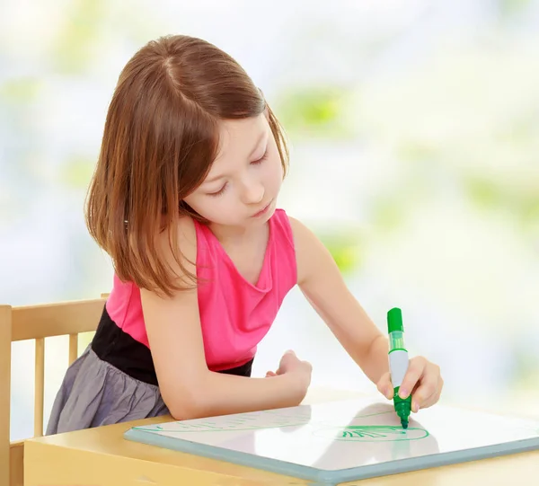 Meisje trekt met de markeerdraad aan de tafel. — Stockfoto