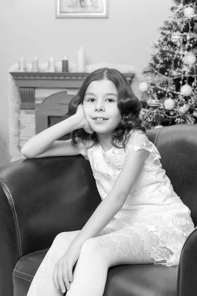 Het kleine meisje in de leunstoel van de kerstboom. — Stockfoto