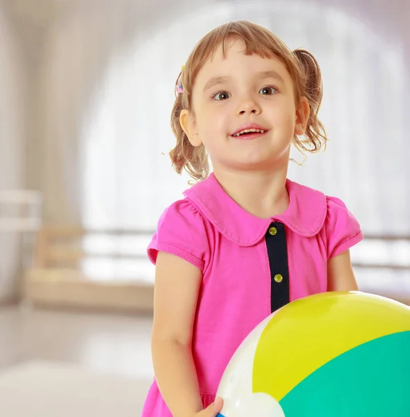 Маленькая девочка с полосатым мячом — стоковое фото