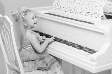 kız beyaz bir kuyruklu piyano üzerinde oynuyor.