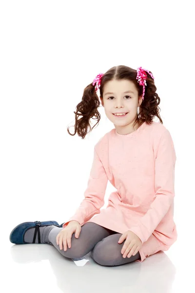 Malá holka sedí na podlaze a narovná vlasy. — Stock fotografie