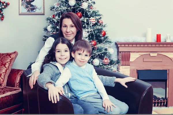 Mother with children by the Christmas tree. — Stock Photo, Image