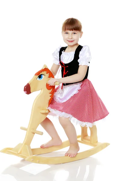 Menina balançando em um cavalo de madeira . — Fotografia de Stock