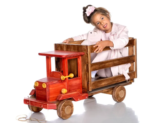 Menina está brincando com um carro de madeira . — Fotografia de Stock