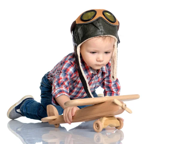 Ein kleiner Junge mit Pilotenmütze und einem Holzflugzeug in der Hand — Stockfoto